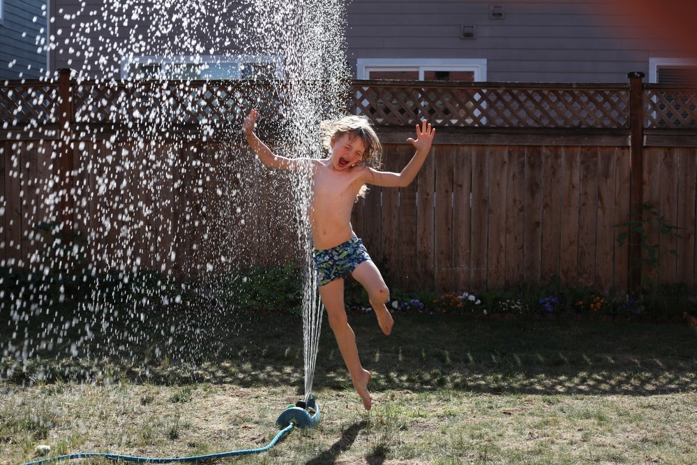 family activities - boy playing with sprinkler in garden