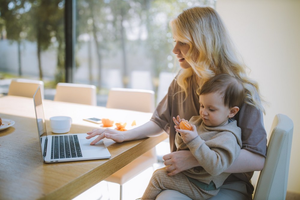 single mum at laptop holding child