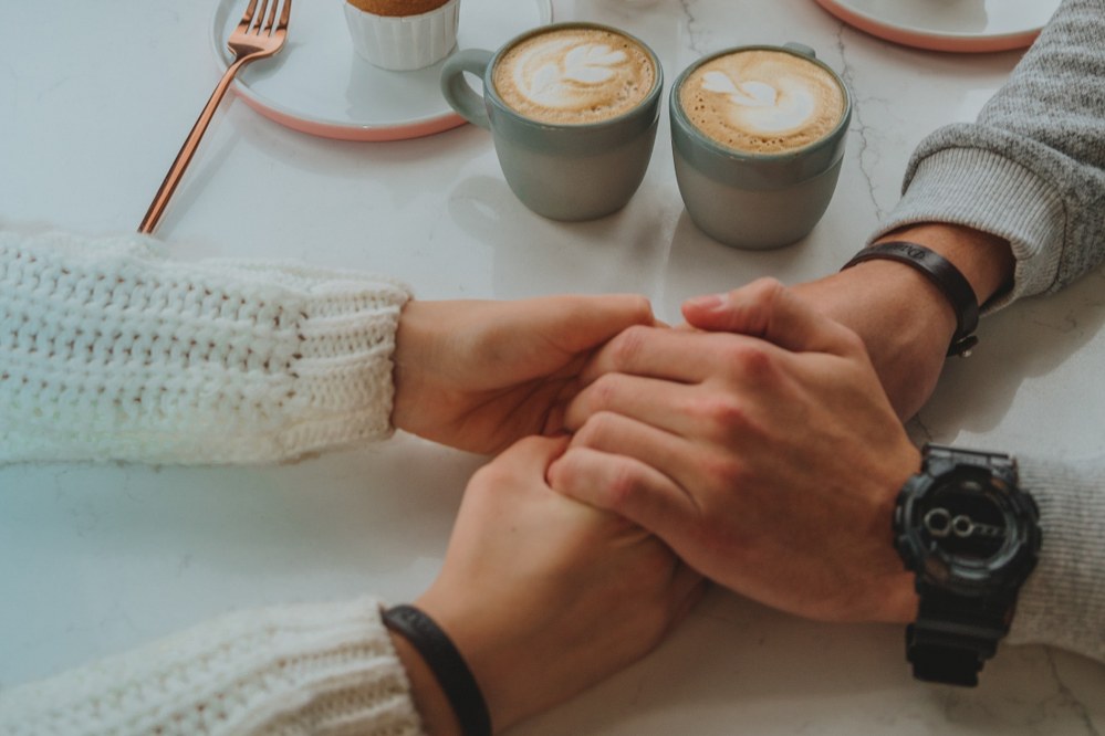 man and woman holding hands over coffee