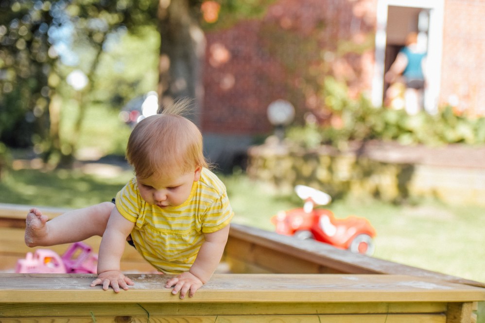 baby playing in sandpit in garden