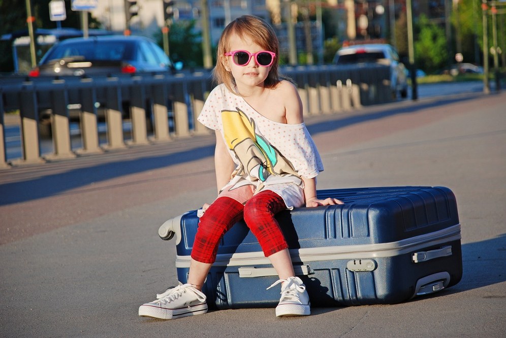 young child sitting on suitcase 