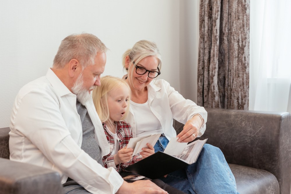 grandparents looking at photo album with young girl