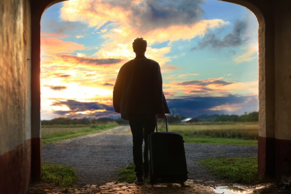 man with suitcase leaving small airport