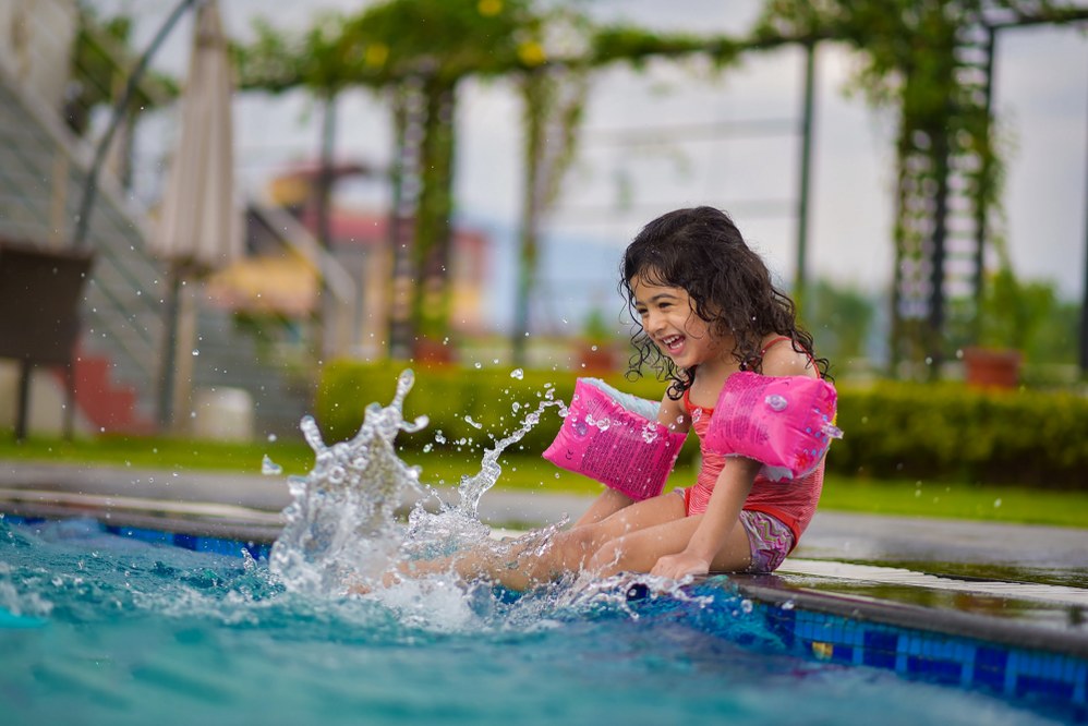 young girl sitting on edge of pool