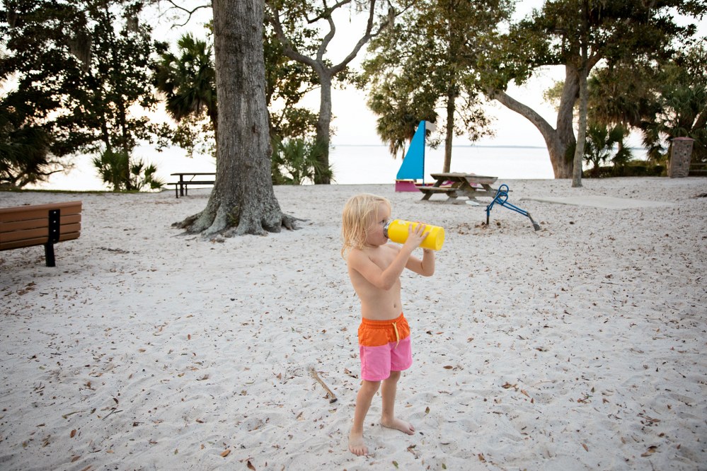 child drinking from water bottle at beach on holiday