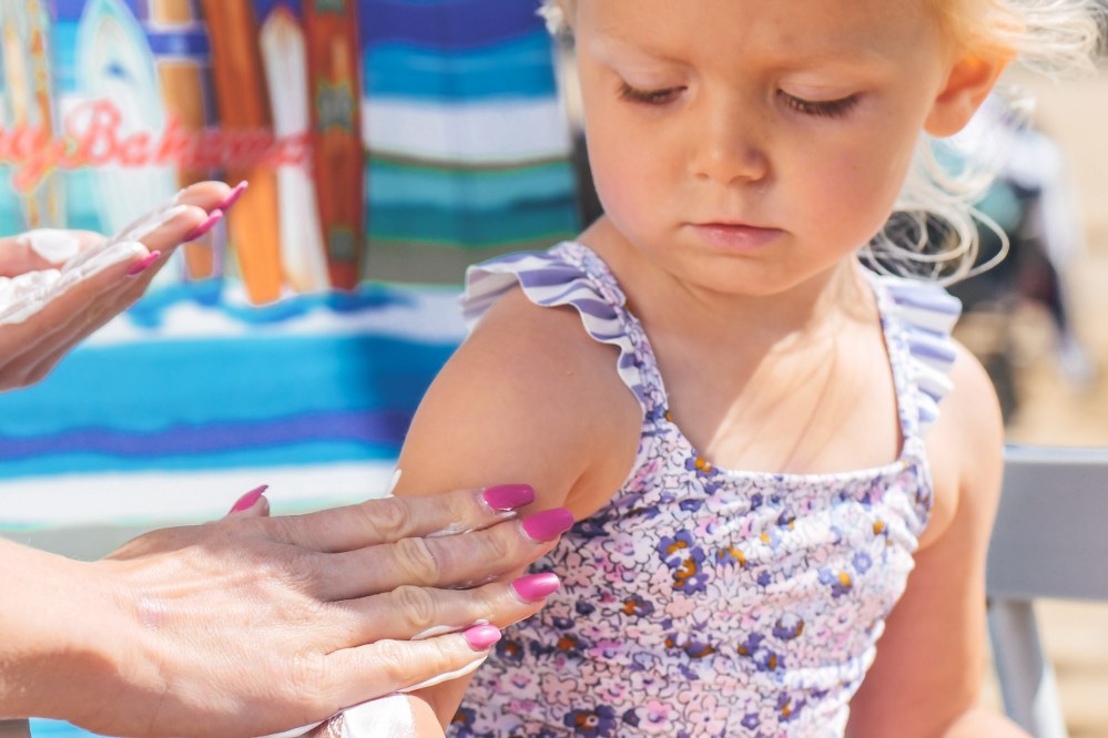 girl having sun lotion applied