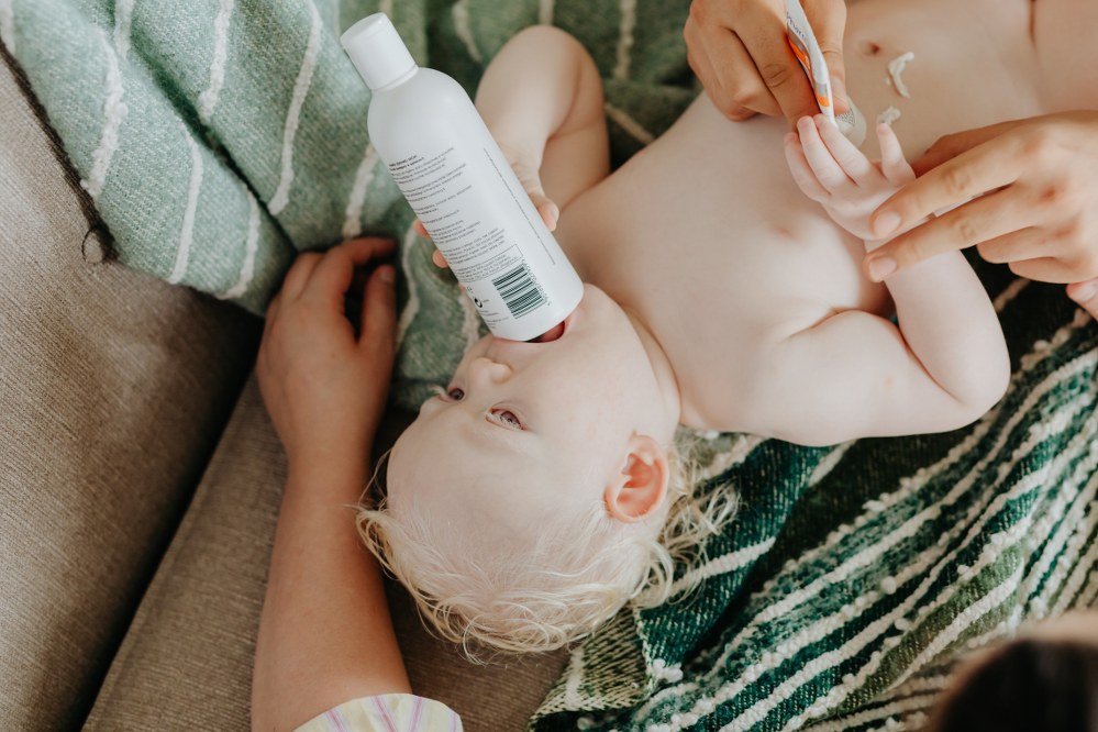 parent putting sun lotion on baby