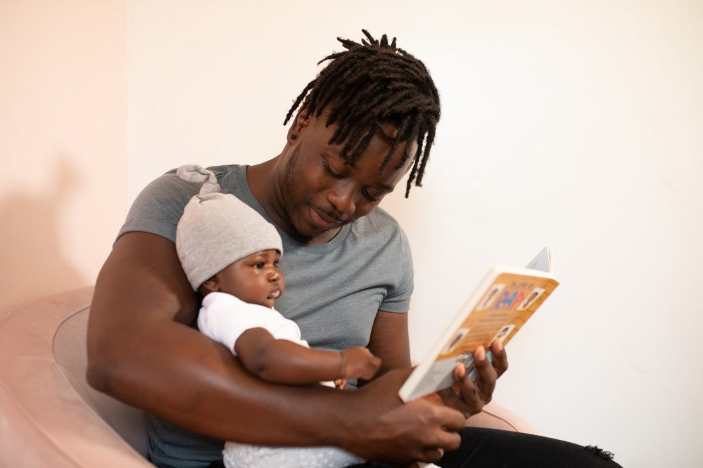 dad reading book to baby on holiday