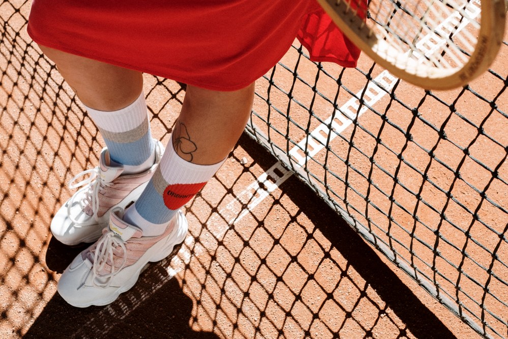 young woman on tennis court wearing light pink trainers